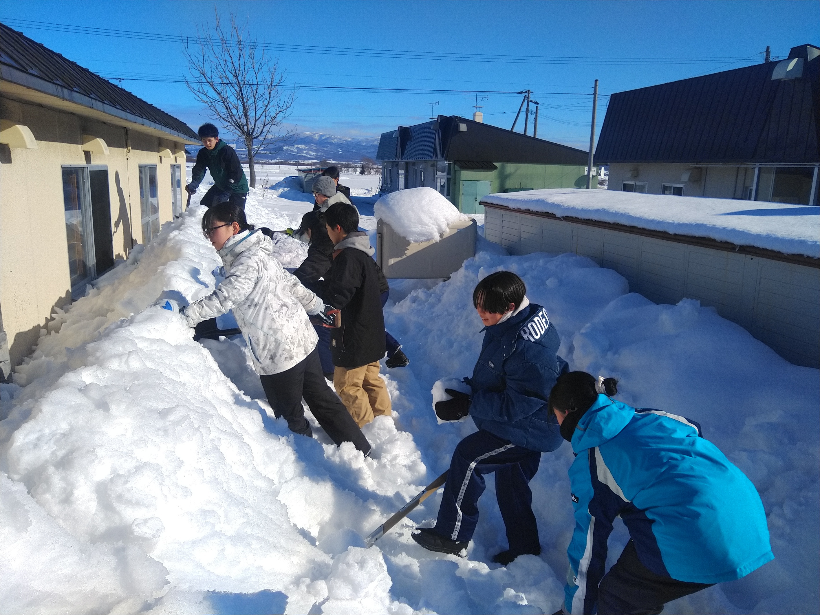高齢者住宅の軒下の雪を取り除く作業