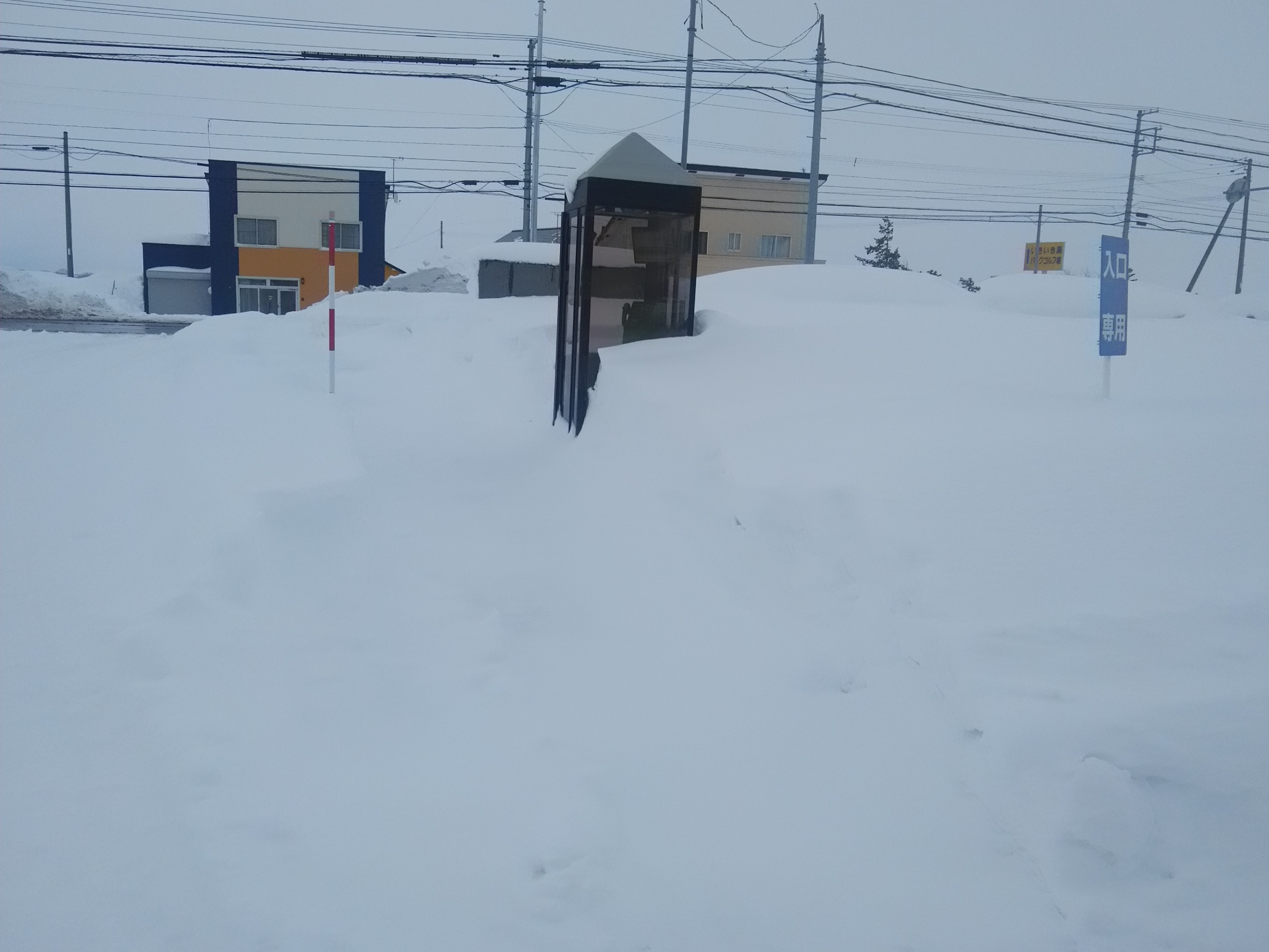 雪に埋もれた校舎前の電話ボックス