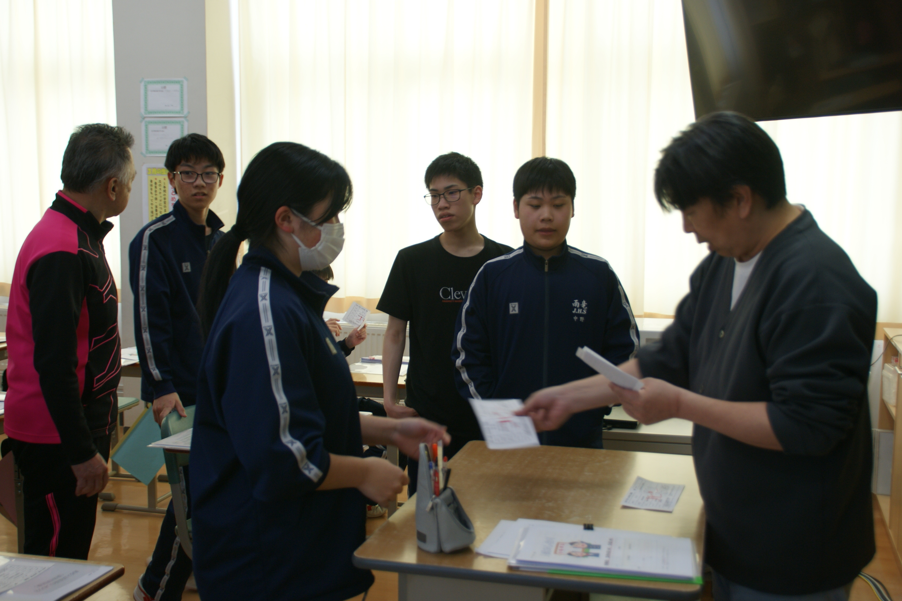 進路担当から受験票を受け取る3年生